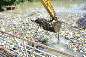 Imagem colorida mostra retirada de lixo e plástico em grande quantidade em rio no entorno de Manaus