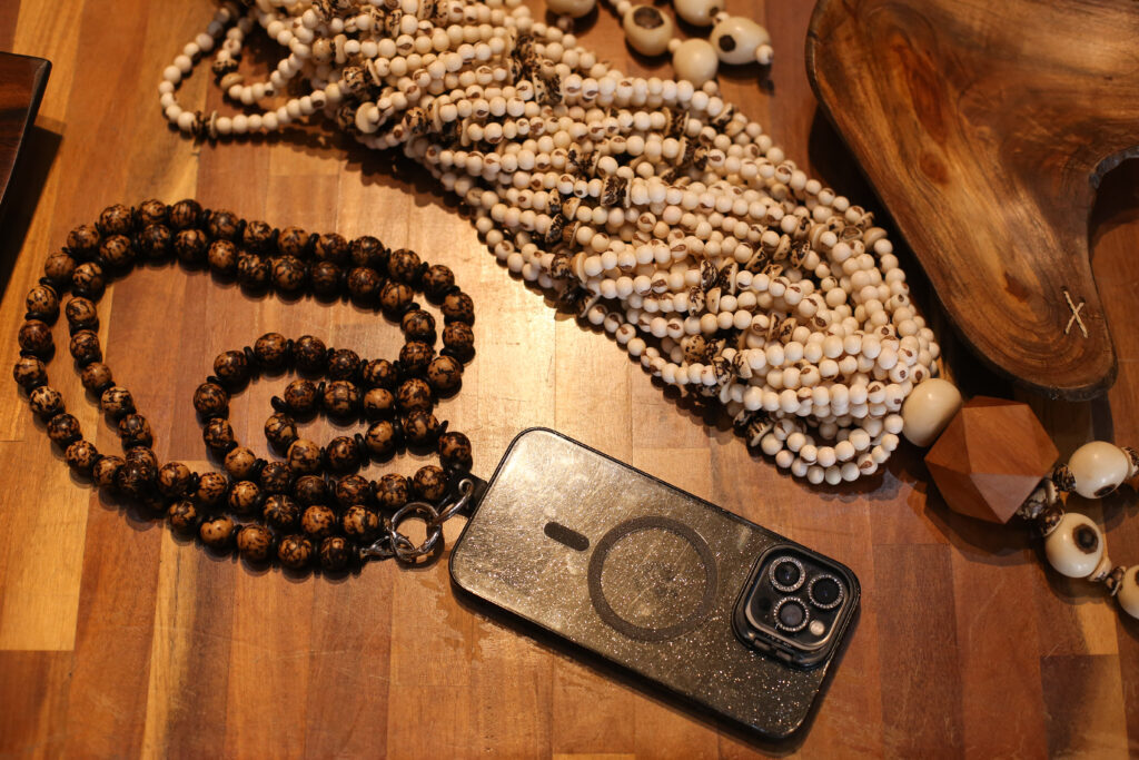 Imagem colorida artesanatos sobre uma mesa de madeira e um celular modelo Iphone