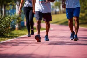 Imagem colorida mostra práticas de saúde como corrida em ângulo fechado com foco em pernas de pessoas correndo para falar sobre o risco do câncer