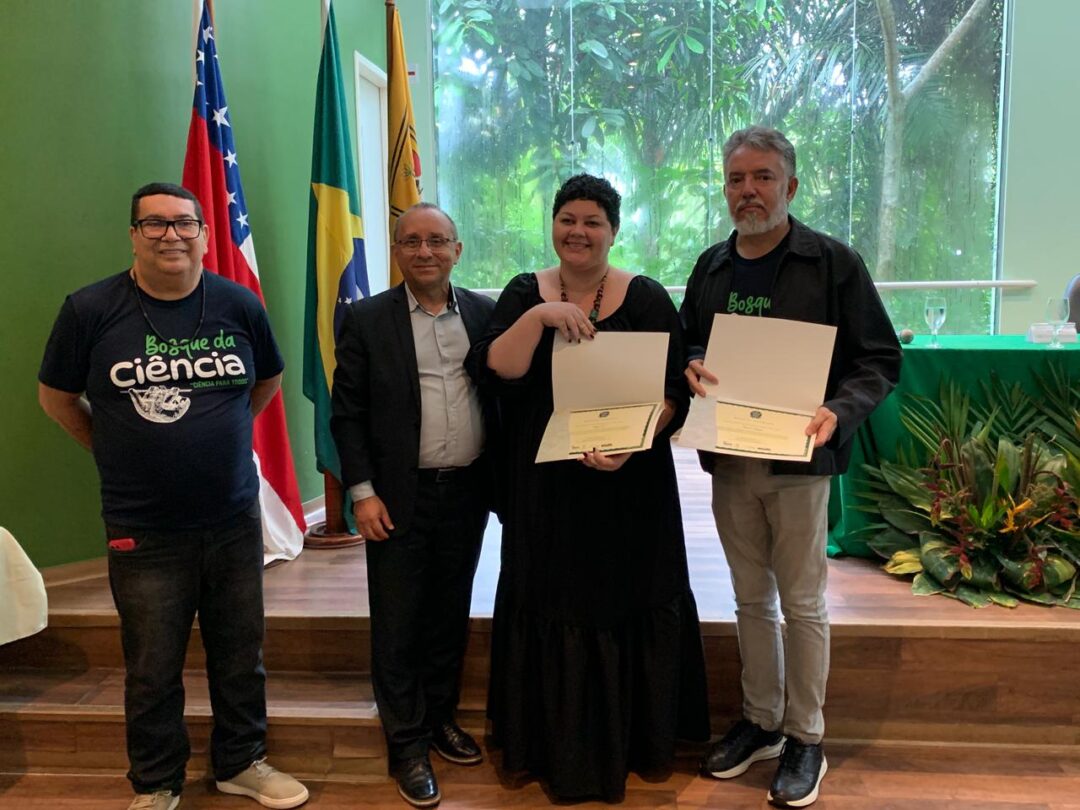 Imagem colorida mostra a supervisora de jornalismo do Portal Amazônia, Clarissa Bacellar, recebendo certificado do Inpa na cerimônia de 31 anos do Bosque da Ciência