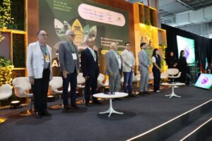 Imagem colorida mostra pessoas levantadas em palco durante palastra da TranspoAmazônia